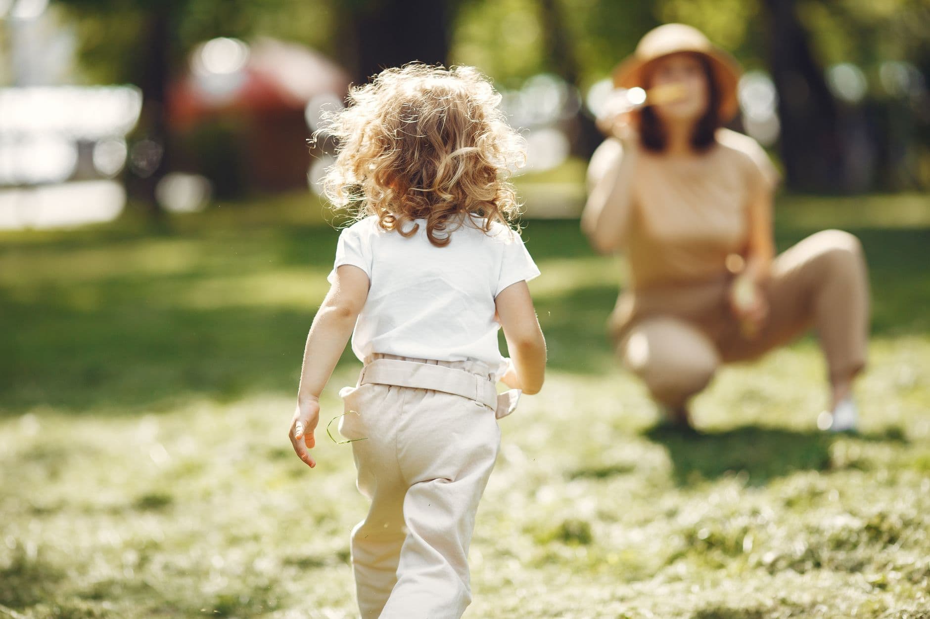 A young child running towards her mother in a sunny park