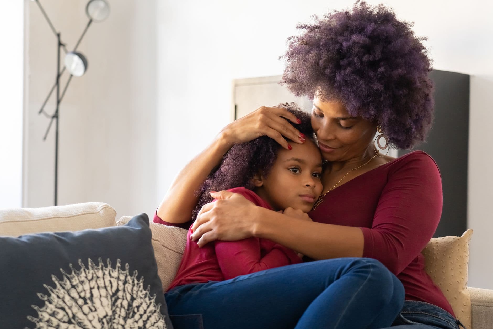 A mother holding her young daughter close, comforting her at home