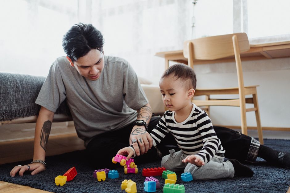 A father and son play with building blocks on the floor