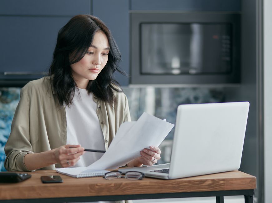 A parent reads through paperwork at a kitchen table