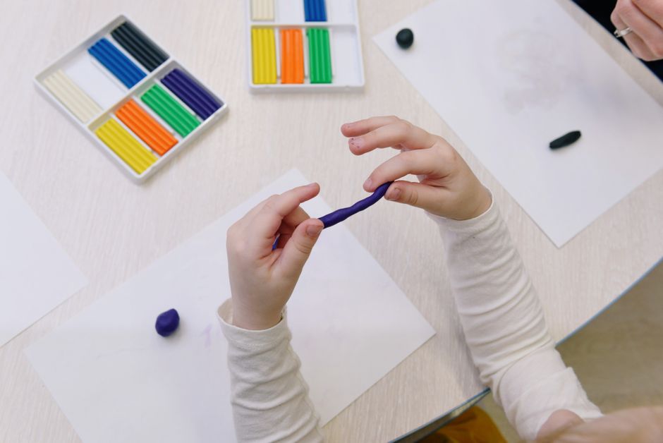 A child working with colourful modelling clay, practising hand strength and fine motor control